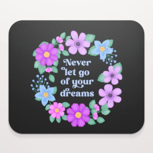 Motivational mouse pad with quote: Never let go of your dreams. Dusty blue text with flowers and foliage on black background.