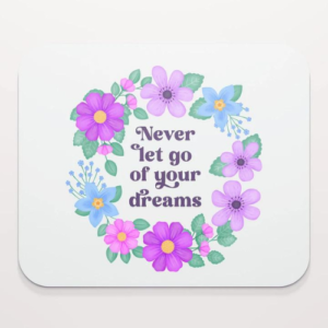 Motivational mouse pad with quote: Never let go of your dreams. Dusty blue text with flowers and foliage on white background.