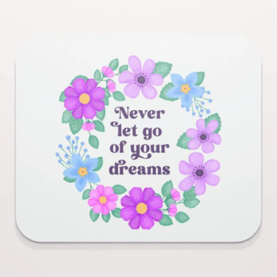 Motivational mouse pad with quote: Never let go of your dreams. Dusty blue text with flowers and foliage on white background.
