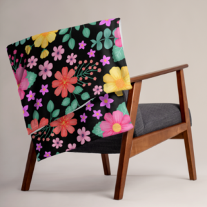 Black floral pattern fleece blanket with pink orange and yellow flowers and green leaves on a black background