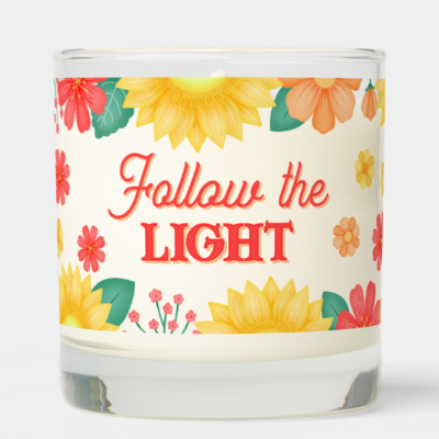 Inspirational candle with motivational quote: Follow the light in script typography and sunflowers with orange daisies and flowers.