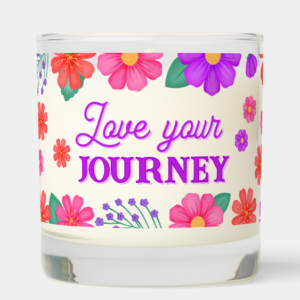 Inspirational candle with motivational quote: Love Your Journey in script typography and purple, pink and yellow flowers.